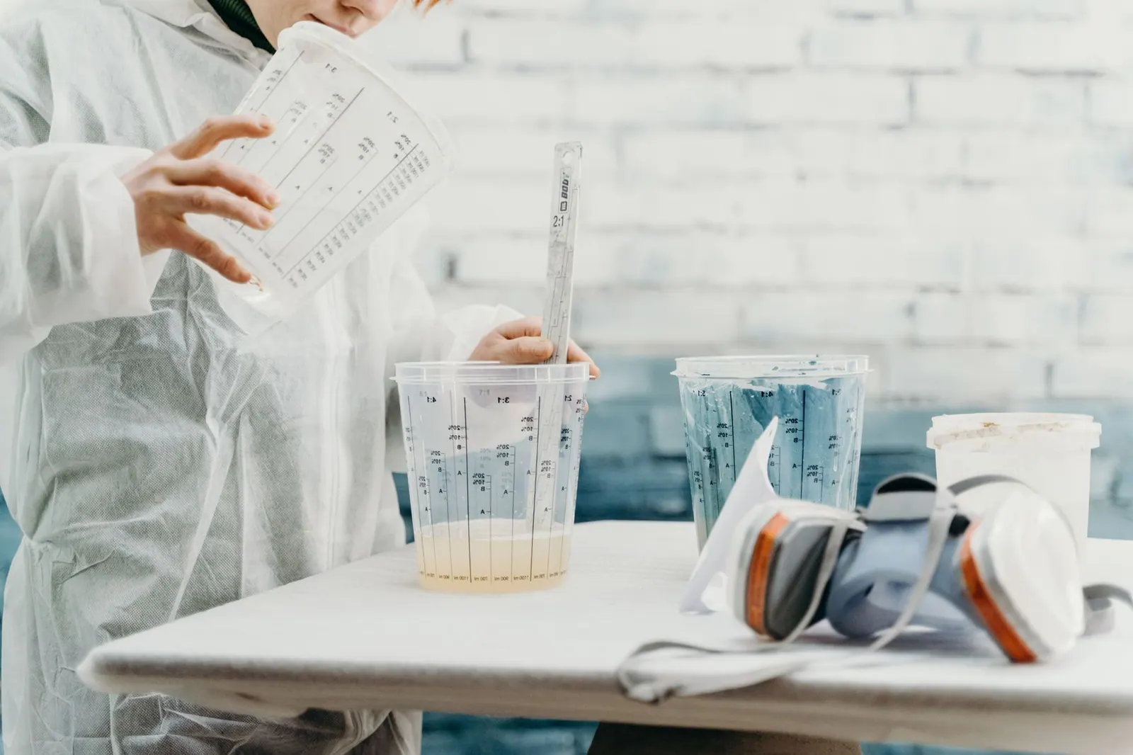 Artist mixing paint in a creative workshop with precise tools and protective gear.