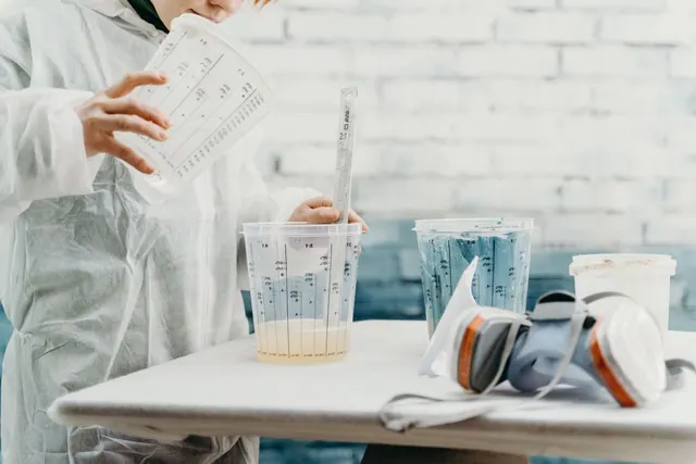 Artist mixing paint in a creative workshop with precise tools and protective gear.